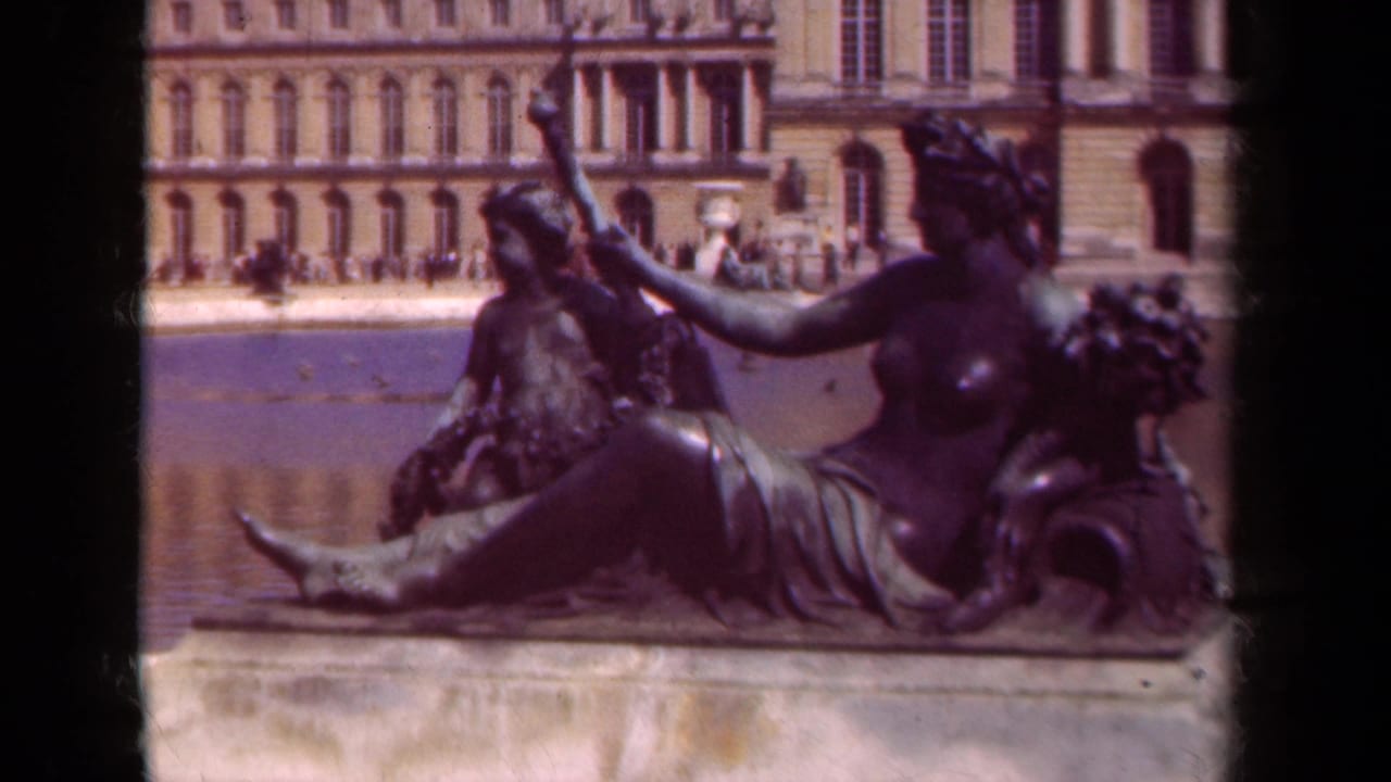 Reclining bronze sculpture fills the foreground with water and palace windows behind it.
