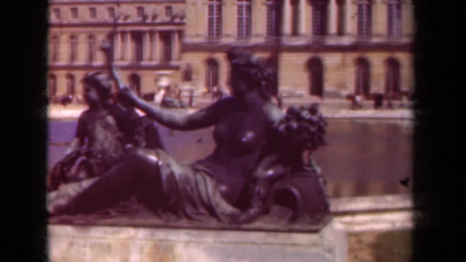 The 8mm frame keeps the bronze garden figures large in the foreground, with Versailles water and palace architecture softly visible beyond.