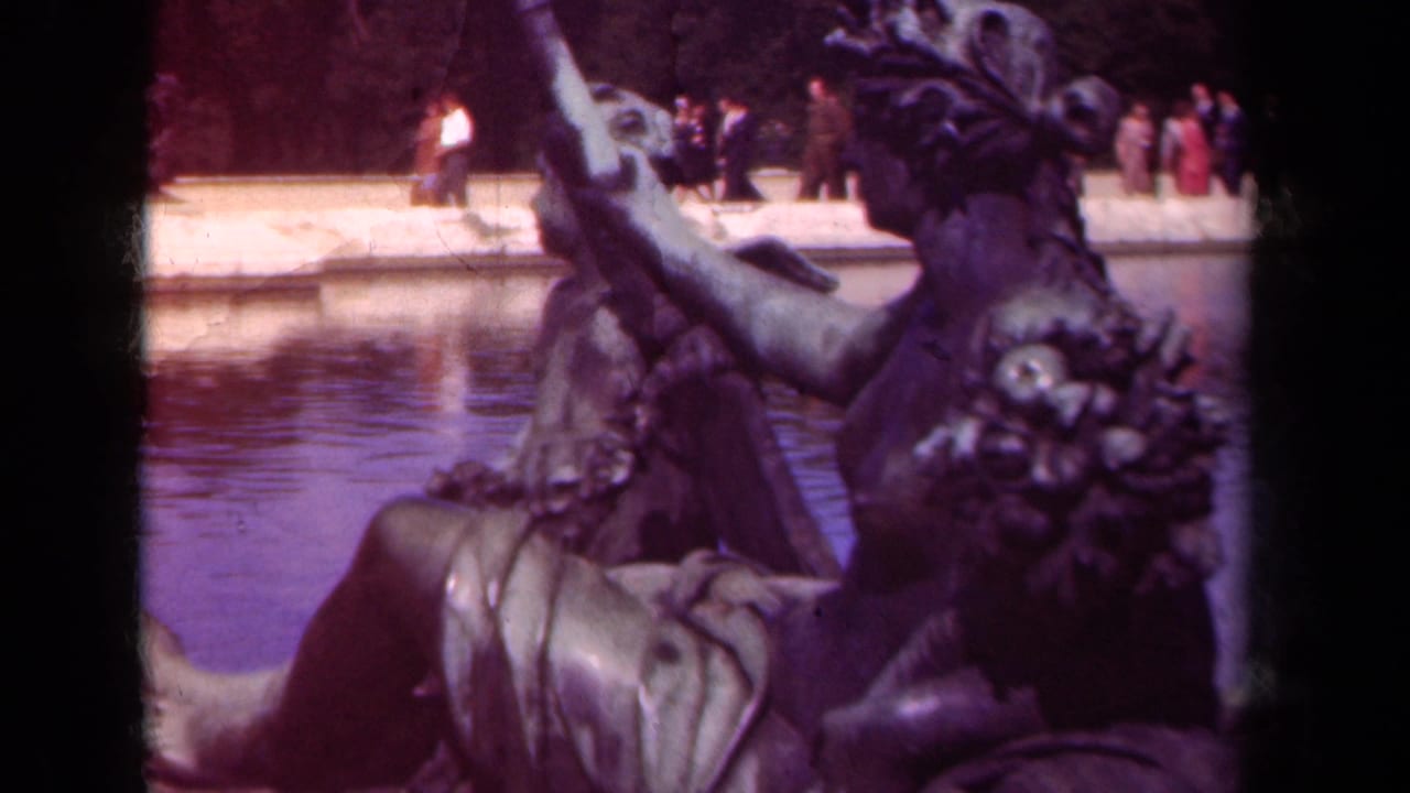 Bronze sculptural figures beside a reflective pool with visitors in the distance.