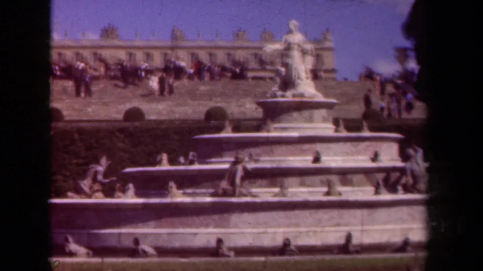1939 Paris frame showing the fountain and upper statue, visitors on the terrace, pale building facade, and dark 8mm vignette.