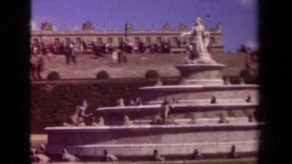 1939 home-movie view of visitors crossing a formal palace garden terrace above an ornate fountain, likely in the Paris area.
