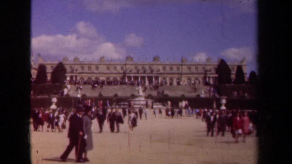 1939 Paris frame with tourist groups scattered across palace grounds, seen from a handheld 8mm visitor perspective.