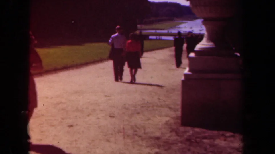 The 1939 Paris garden view shows the couple from behind, with the path, urn, lawn, and background walkers still visible.