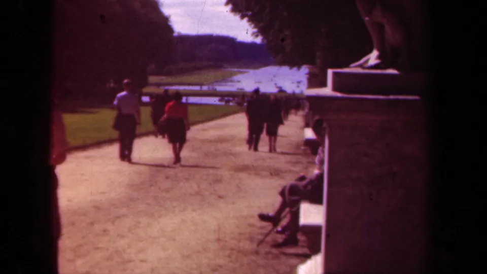 In the Paris park scene, visitors walk toward a distant water feature while one person sits near the right-hand wall.