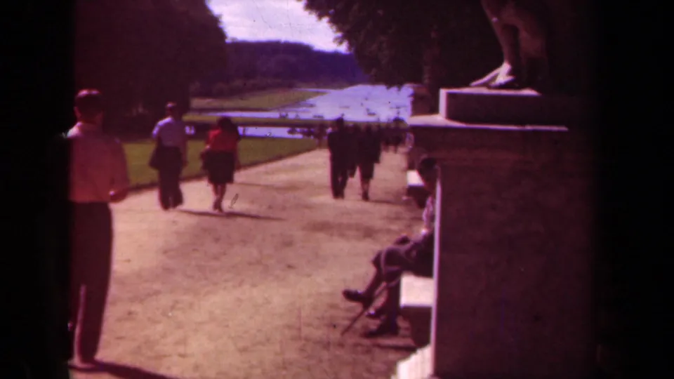 The final frame keeps the formal Paris park path in view, with walkers, a seated visitor, lawns, trees, and a reflective water feature.