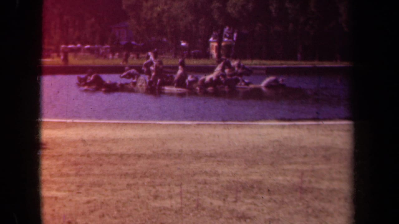 1939 Paris frame of an equestrian fountain group viewed from across the basin, with a tree-lined park area and distant visitors behind it.