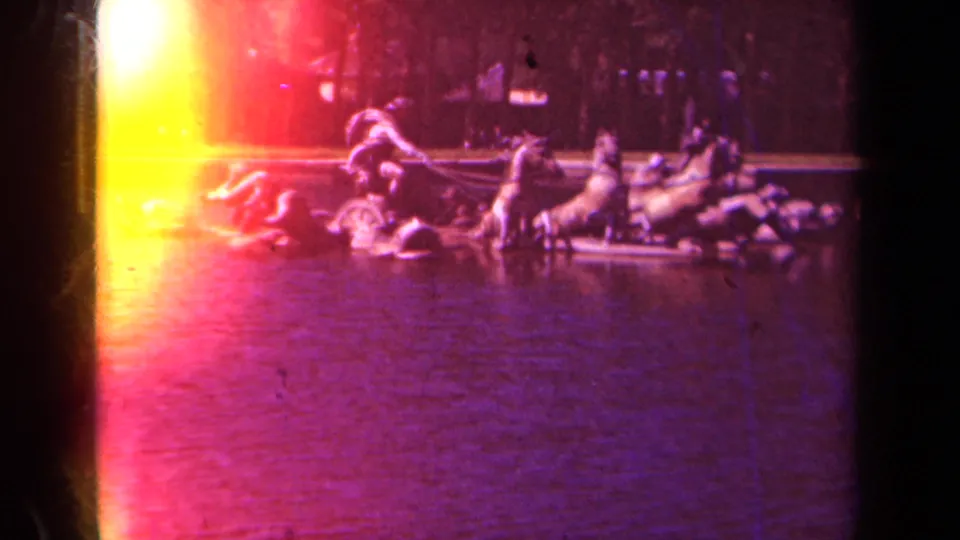 1939 Paris home-movie frame with a closer view of the horse-and-figure fountain sculpture, partly washed by bright yellow-red film flare.