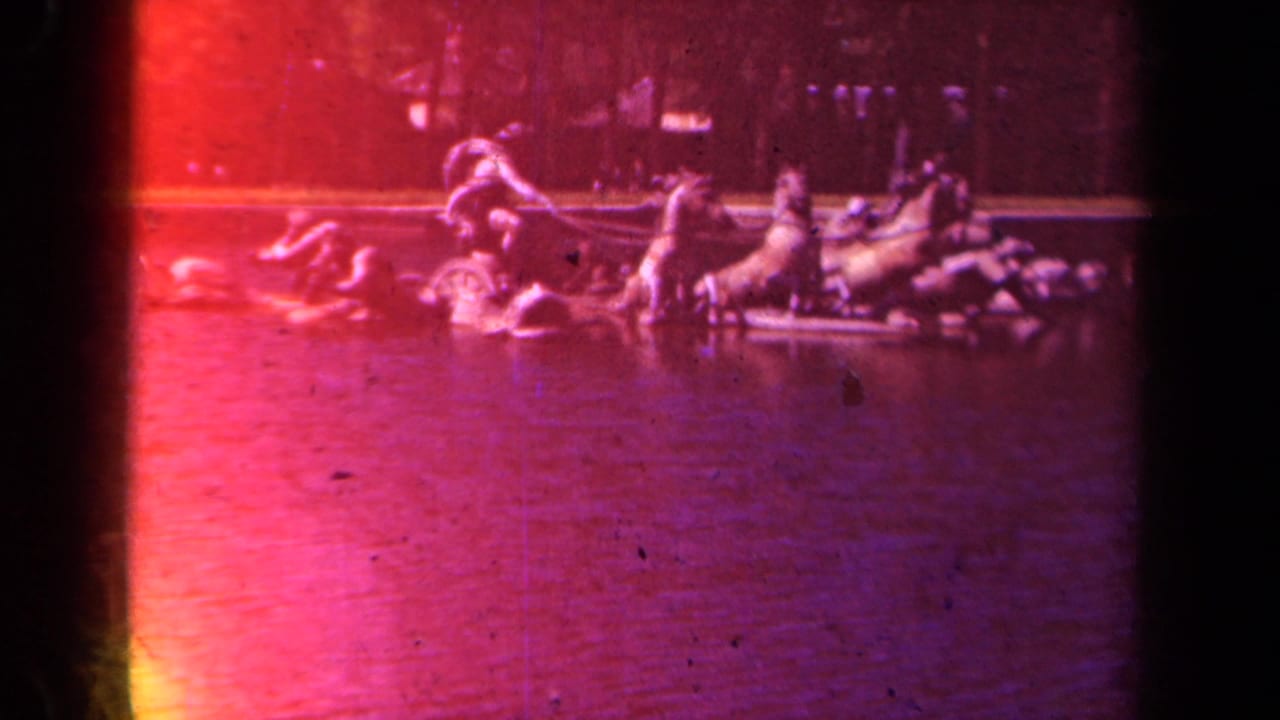 1939 8mm Paris garden view with a distant ornamental fountain or sculpture, water, trees, and strong red exposure flare.