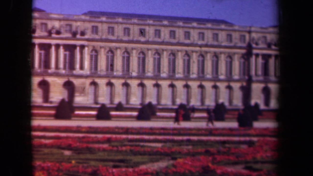1939 8mm view in Paris, France, showing a grand historic facade, formal gardens, and small visitor figures in front.