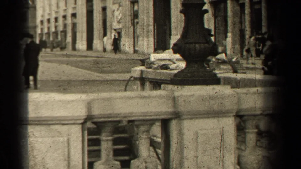 1947 Paris street view showing pedestrians on a sidewalk beside stone facades, a lamp base, curb railing, and heavy frame shadow.