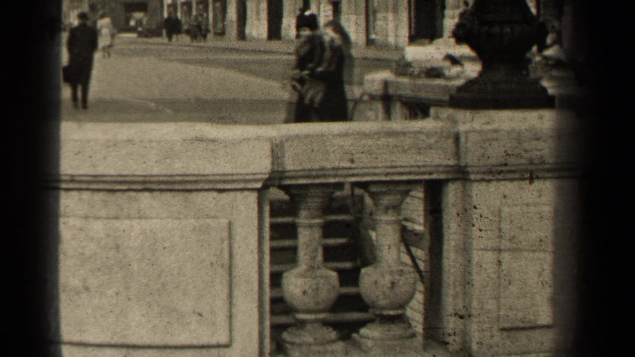 Elevated 1947 Paris street view with a stone balustrade in front and pedestrians moving along the pavement beyond.