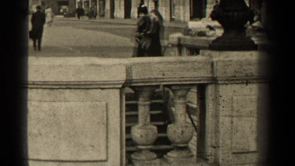 Elevated 1947 Paris street view with a stone balustrade in front and pedestrians moving along the pavement beyond.