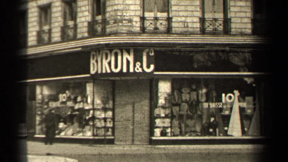 Closer 1947 Paris view of the BYRON & C storefront, showing window merchandise, mannequins, sale signage, and passing street activity.