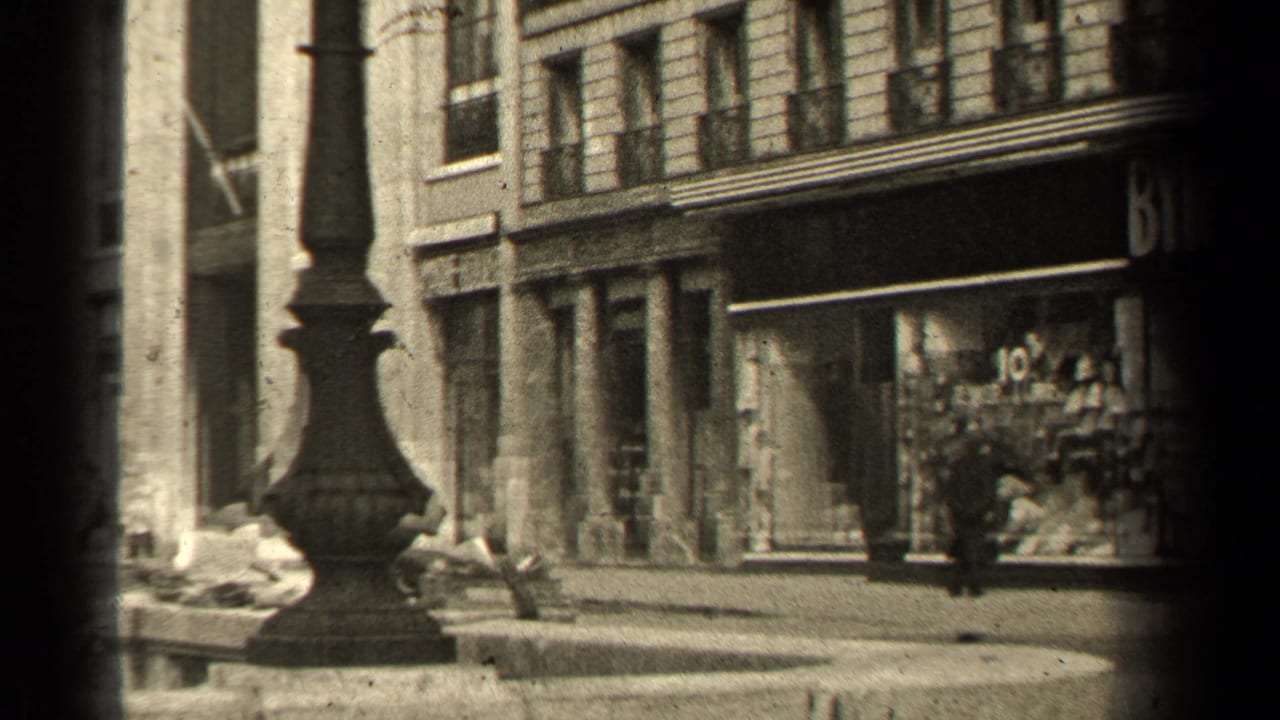 1947 Paris street frame with a dark lamppost in the foreground, shopfront glazing, stone facades, and partial Byron signage.