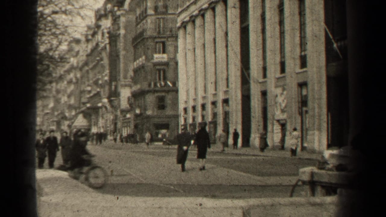 A cyclist passes in front of pedestrians and tall city buildings.