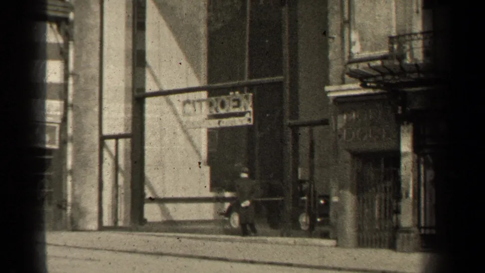 Paris street view from 1947 metadata, showing pedestrians, a Citroen sign, shop windows, masonry frontage, and soft black-and-white film texture.