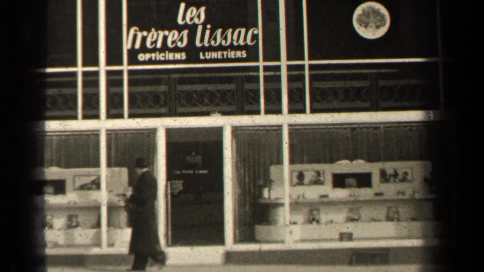 1947 Paris storefront view showing Les Freres Lissac opticians and lunetiers signage, display windows, a pedestrian, and dark 8mm frame edges.