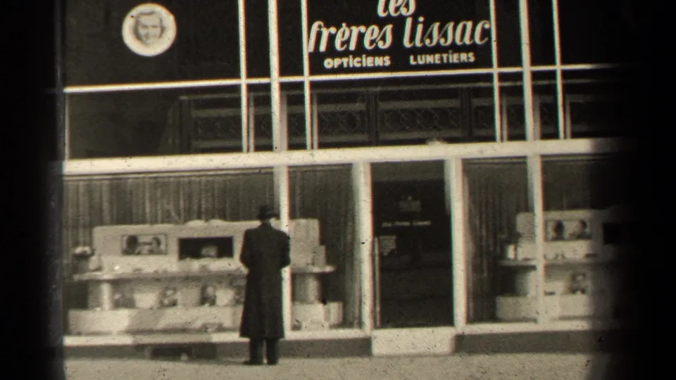 Rear view of the passerby at the Les Freres Lissac optician window in Paris, with display cases and signage visible.