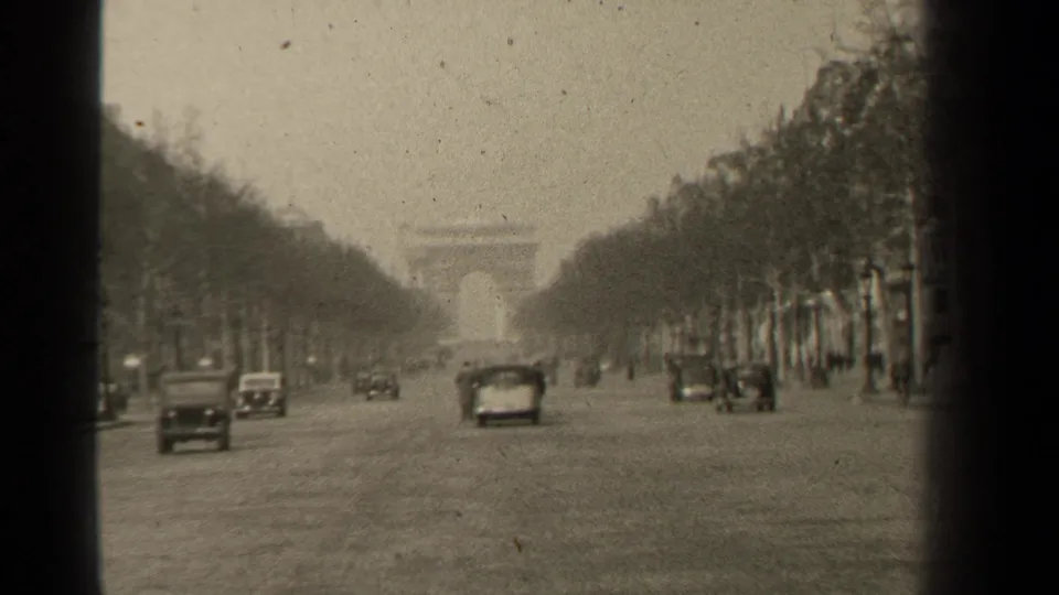1947 8mm view down the Champs-Elysees toward the Arc de Triomphe, with cars moving along the broad roadway.