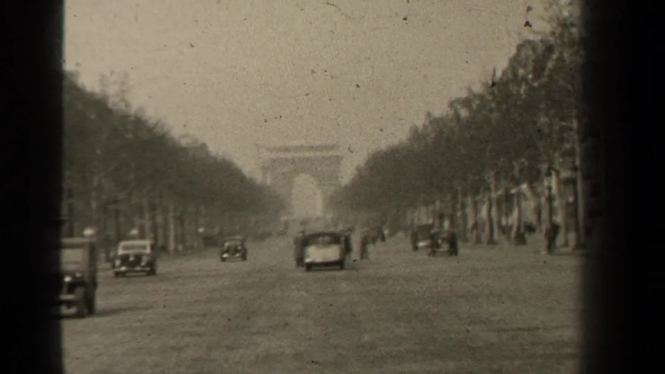 Paris street view from 1947 showing traffic on the Champs-Elysees, rows of trees, and the Arc de Triomphe beyond haze.
