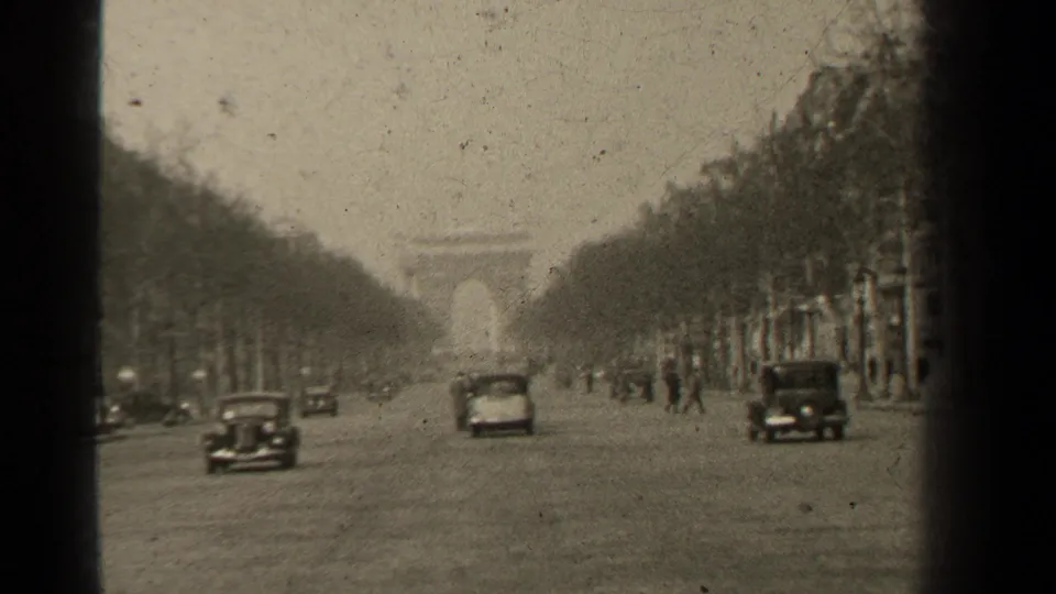 1947 Paris 8mm frame showing multiple classic cars on the Champs-Elysees and the Arc de Triomphe centered in the background.
