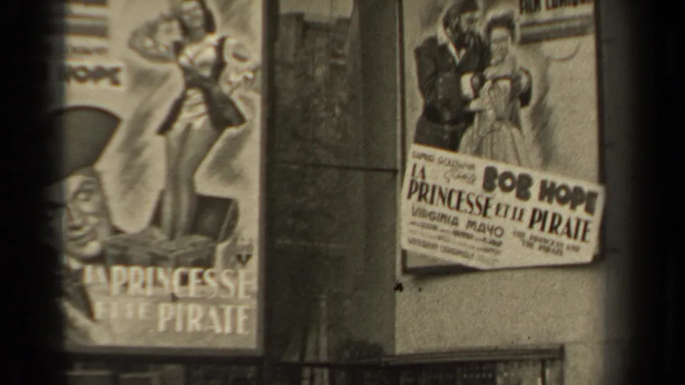1947 Paris footage showing La Princesse et le Pirate posters on a weathered wall, with Bob Hope text and illustrated figures partly visible.