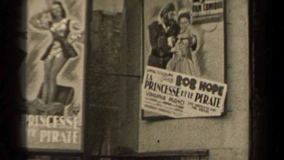 A French poster for La Princesse et le Pirate is seen on a wall, naming Bob Hope and Virginia Mayo with illustrated characters above the title.