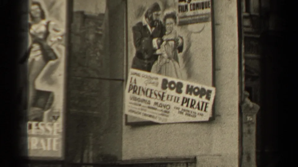 The handheld 8mm view shows adjacent Paris movie posters, including a cropped La Princesse et le Pirate poster and a clearer Bob Hope credit panel.
