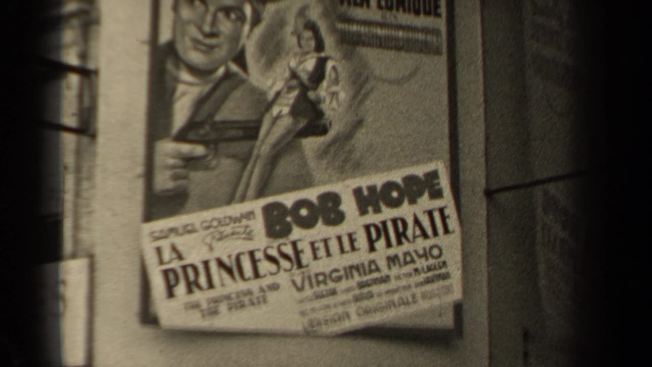 1947 Paris street view showing a French poster for a Bob Hope film, with dark 8mm frame edges and part of a building wall.