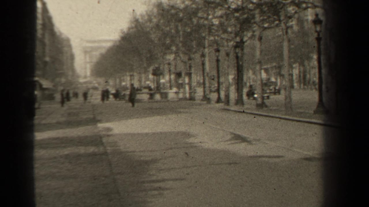 Forward view down the boulevard toward a distant arch-like landmark with pedestrians and traffic nearby.