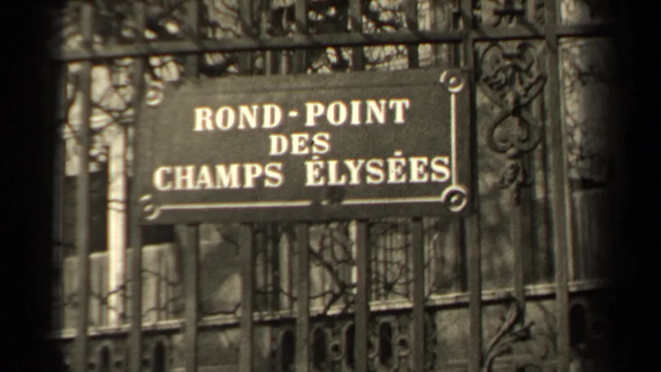 1947 Paris frame showing the Rond-Point des Champs Elysees street sign seen through decorative ironwork.