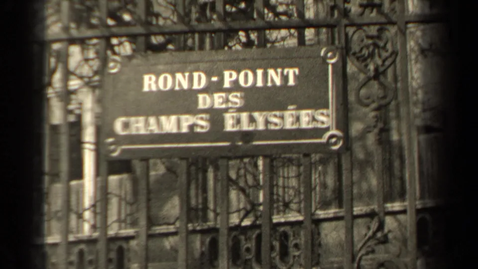 Close 8mm view of the Rond-Point des Champs Elysees sign in Paris, partially blocked by dark iron bars.
