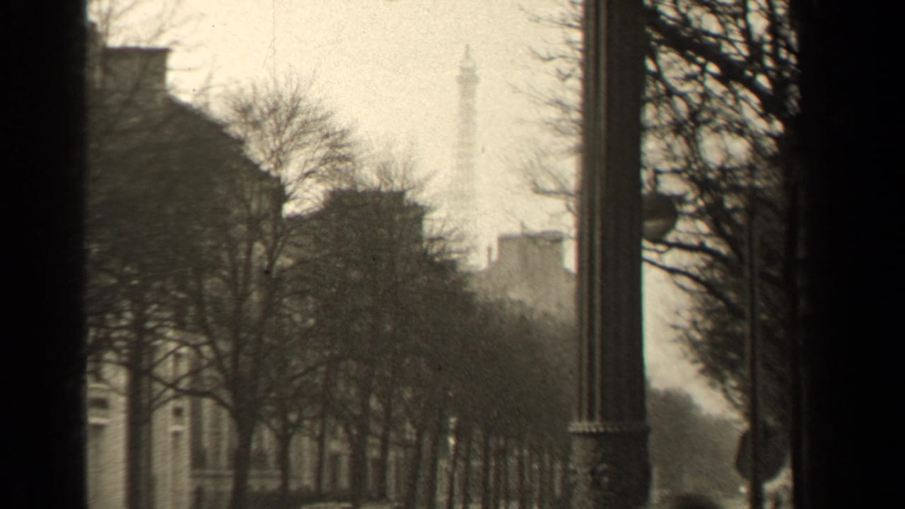 1947 Paris street view with the Eiffel Tower faintly visible behind bare trees, buildings, and a tall foreground lamppost.