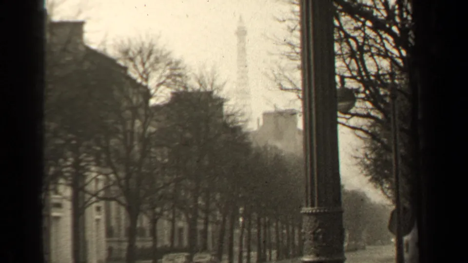 Paris, France street scene from 1947 showing the Eiffel Tower in the distance, framed by bare trees and a lamppost.
