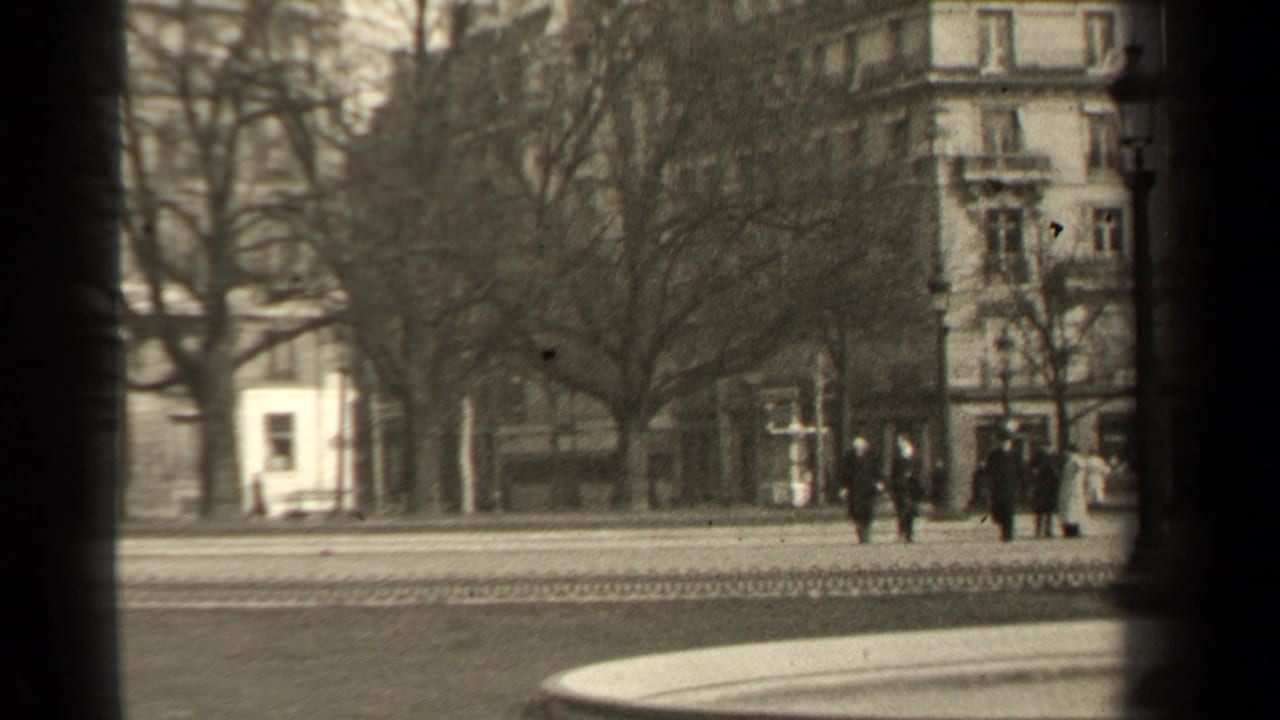 1947 Paris street frame with pedestrians grouped near the right side, bare trees, a pale building, and an ornate corner facade.