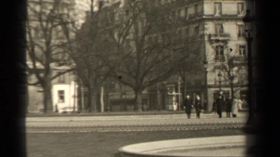 1947 Paris street frame with pedestrians grouped near the right side, bare trees, a pale building, and an ornate corner facade.