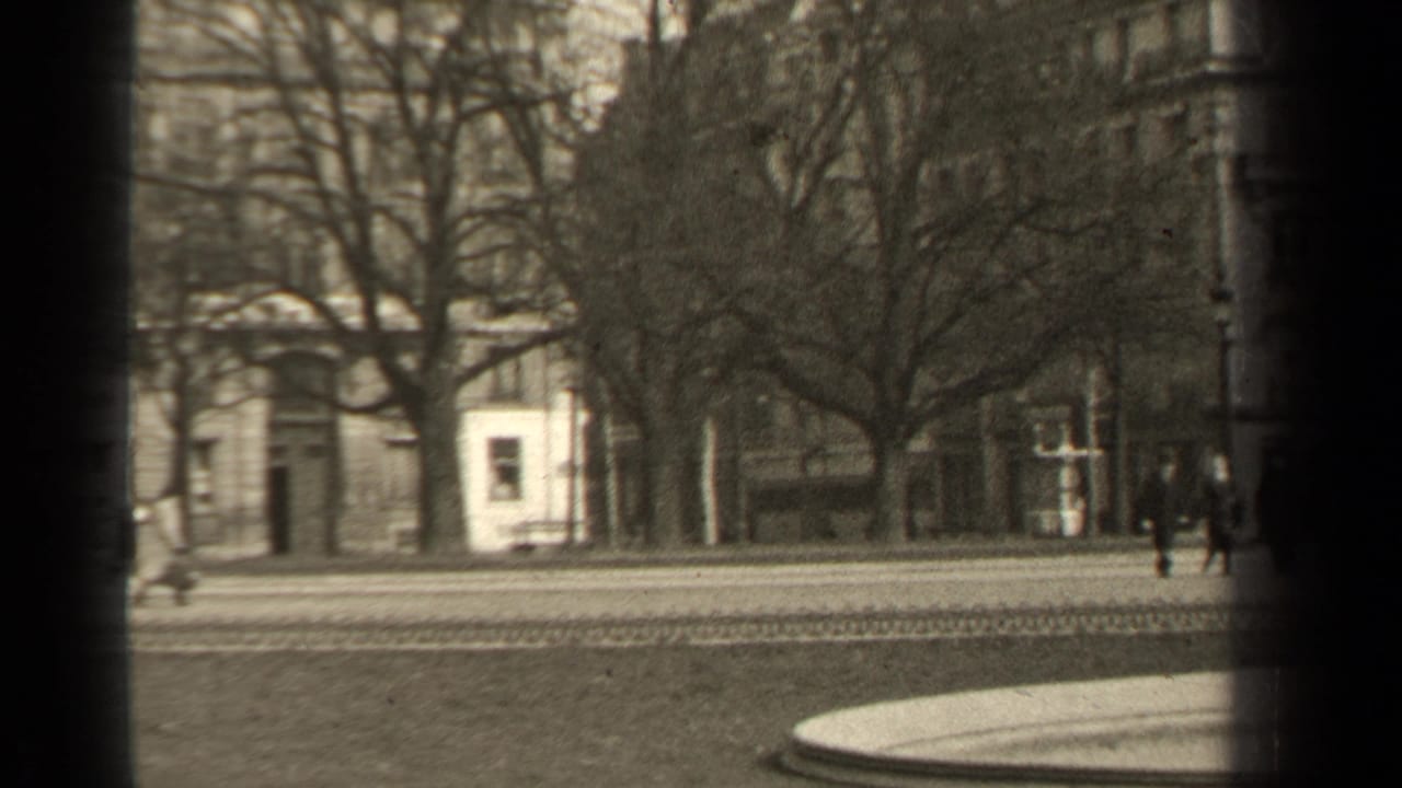 1947 Paris street view with pedestrians near a tree-lined roadway, masonry facades, and dark 8mm frame edges.