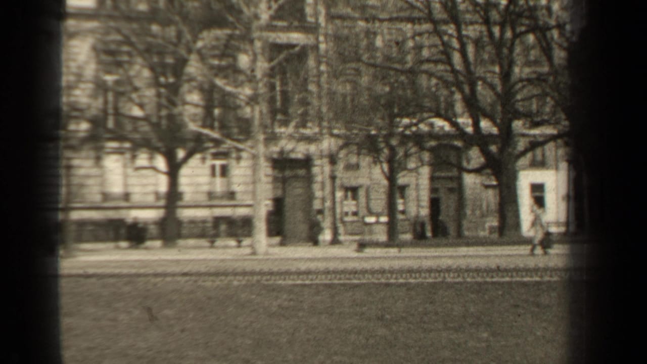 1947 Paris street scene with distant pedestrians, bare trees, road tracks, and formal masonry building fronts.