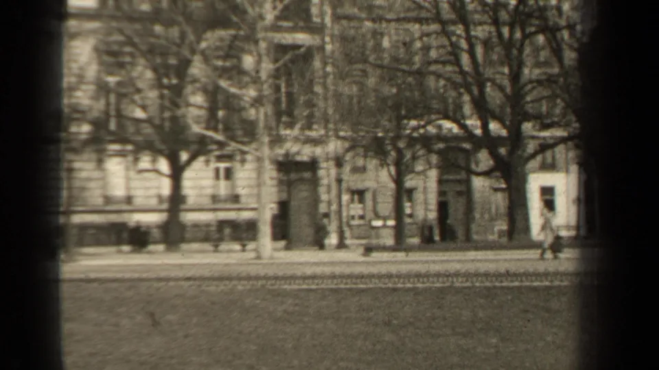 1947 Paris street scene with distant pedestrians, bare trees, road tracks, and formal masonry building fronts.