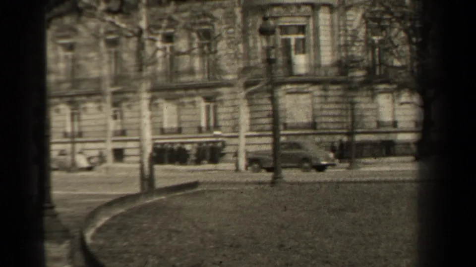 1947 Paris street view with a curved road edge, park lawn, bare trees, street lamps, and a stone building facade.