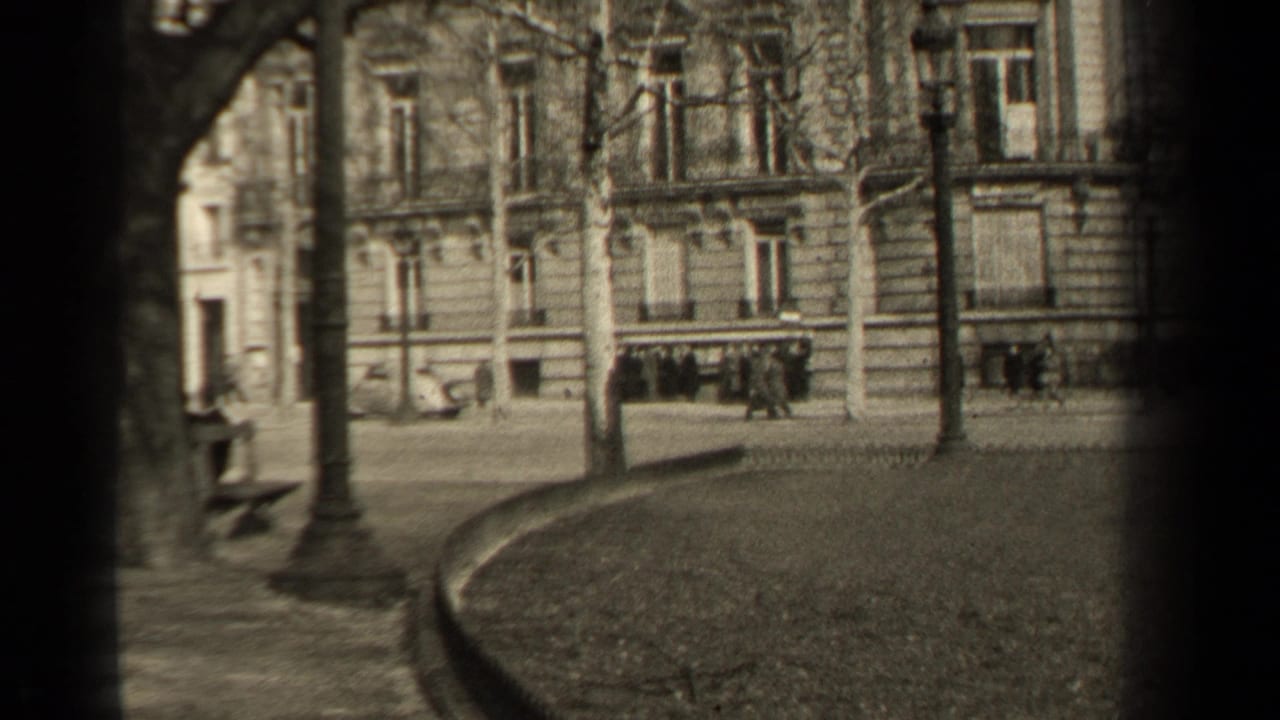 1947 Paris frame with distant pedestrians near a boulevard, bare trees, street lamps, and ornate stone building fronts.