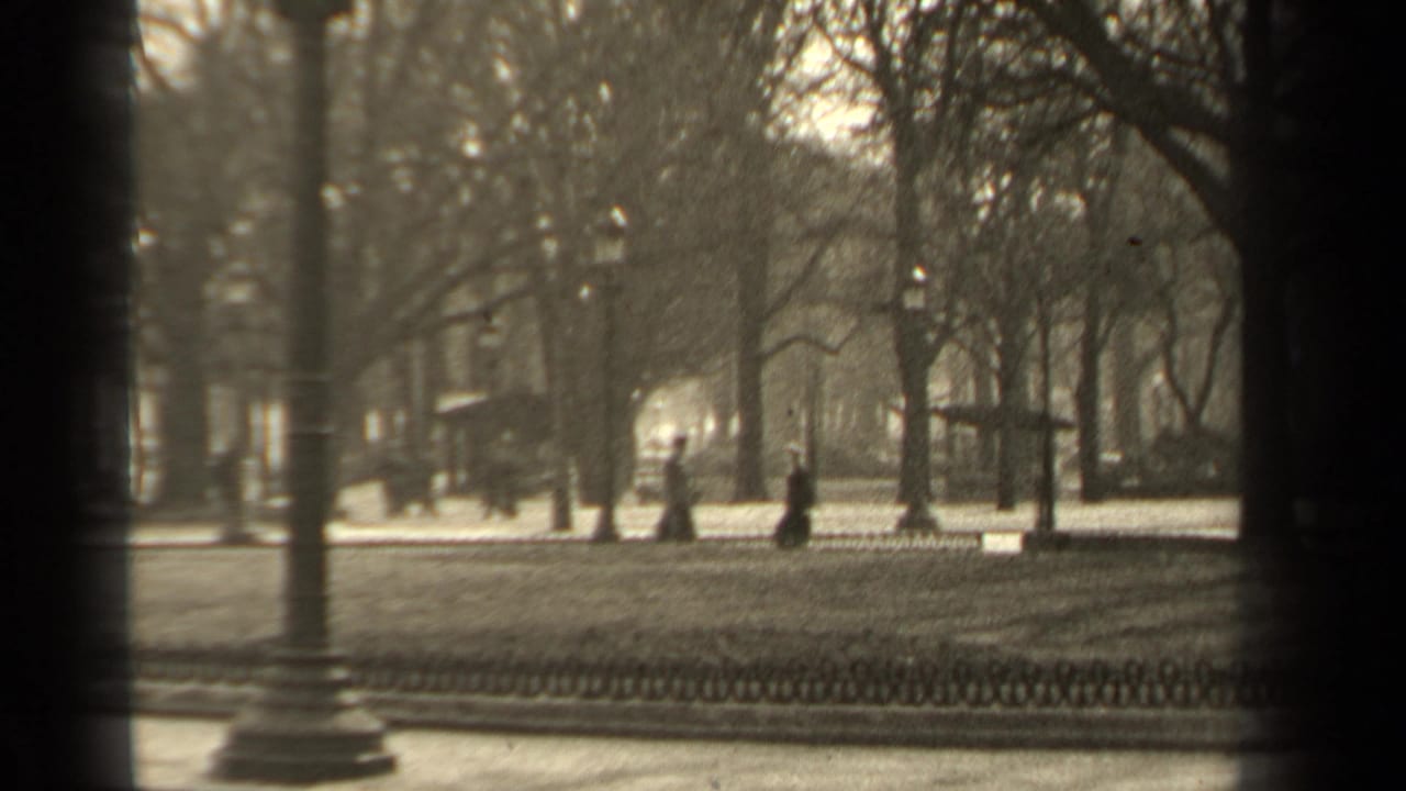 1947 Paris park view with bare trees, ornate lampposts, low fencing, and small distant figures along a paved path.