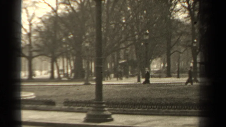 Paris park scene from 1947 showing bare trees, low railings, a lamppost base, and indistinct pedestrians beyond the path.