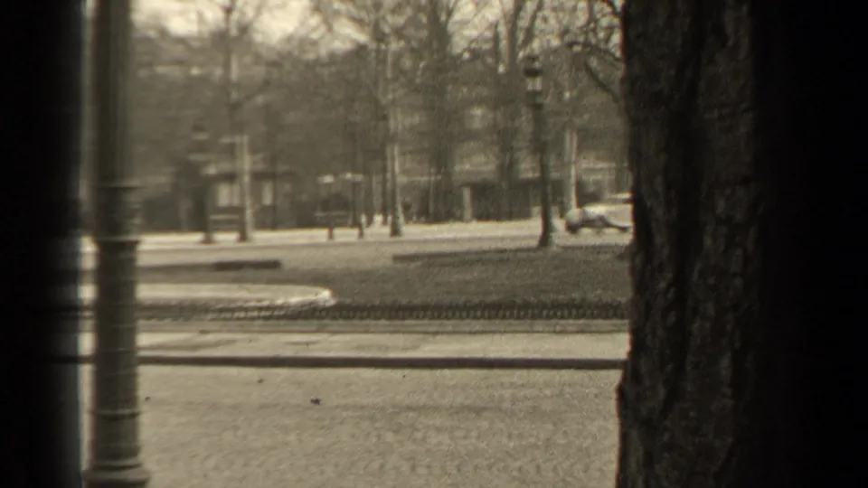 1947 Paris street view with automobiles near tree-lined boulevards, stone facades and a dark vertical foreground obstruction.