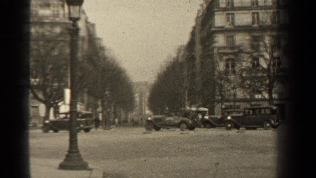Paris street footage from 1947 metadata showing automobiles near a curb, tree rows, apartment facades and soft 8mm grain.