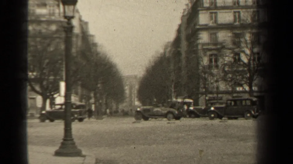 Paris street footage from 1947 metadata showing automobiles near a curb, tree rows, apartment facades and soft 8mm grain.