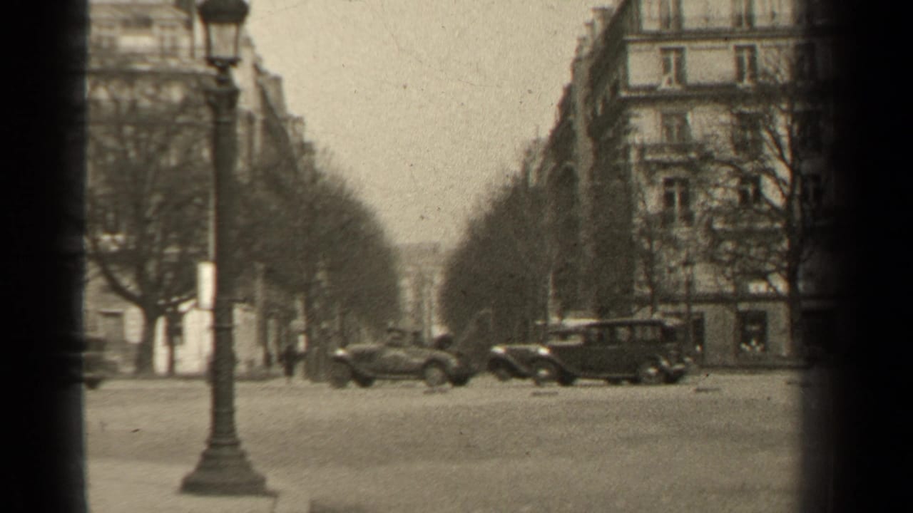1947 Paris street view with classic cars crossing a broad boulevard, bare trees, lamppost, and Haussmann-style buildings.