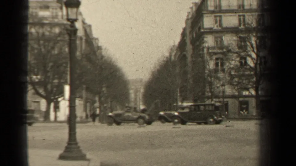 1947 Paris street view with classic cars crossing a broad boulevard, bare trees, lamppost, and Haussmann-style buildings.