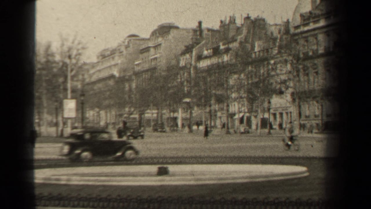 Wide 1947 Paris boulevard view with a passing car, cyclist, pedestrians, lamppost, bare trees, and rows of apartment buildings.