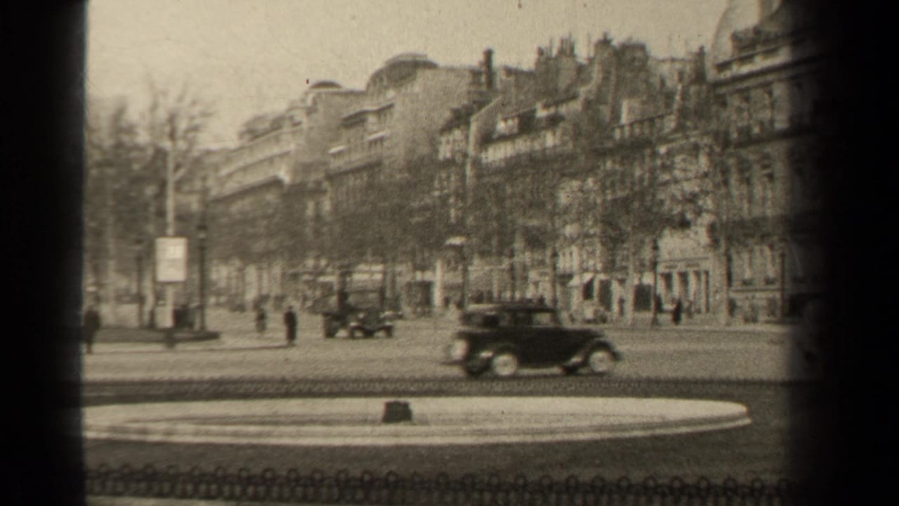 1947 Paris street view with period cars, pedestrians, bare trees, and stone building facades seen from an 8mm home-movie angle.